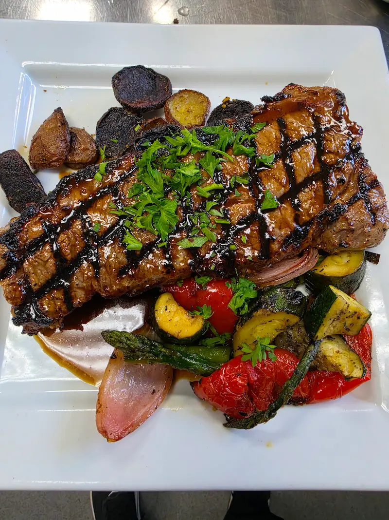 14 ounce boneless striploin steak served with roasted potatoes and seasonal vegetables.