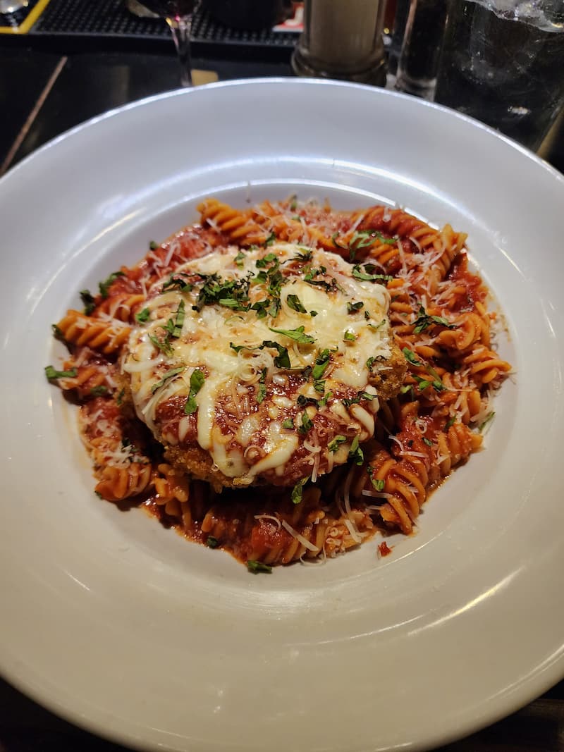 Chicken Parmesan served with fettuccine in tomato sauce.