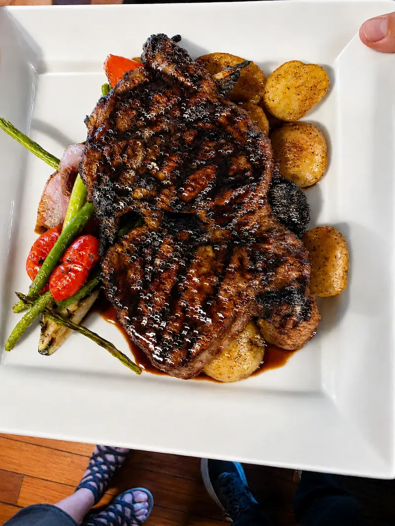 Ribeye steak served with roasted potatoes and grilled vegetables.